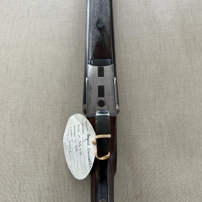 espingarda com madeira escura e metal prateado com etiqueta manuscrita