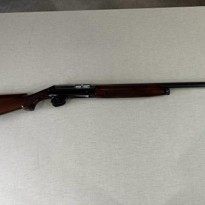 Espingarda de madeira castanha com cano preto sobre fundo cinza claro