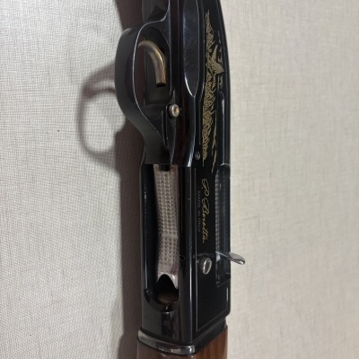 Espingarda com empunhadura em madeira e detalhes metálicos, com gravação dourada e texto Patented e P. Beretta MADE IN ITALY.