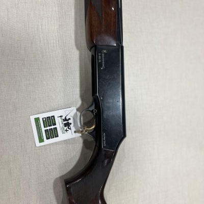 Espingarda com coronha em madeira e cano negro sobre fundo claro.