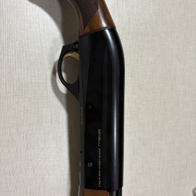Parte de espingarda com cabo em madeira e corpo em metal preto com texto BENELLI ARMI-URBINO-MADE IN ITALY