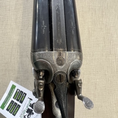 Espingarda de canos lado a lado com detalhes gravados prateados e alavancas