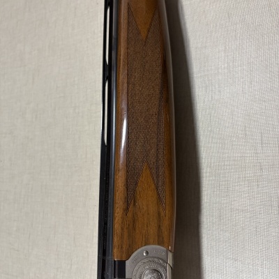 Coronha de madeira castanha com padrão geométrico e mecanismo metálico decorado em espingarda.