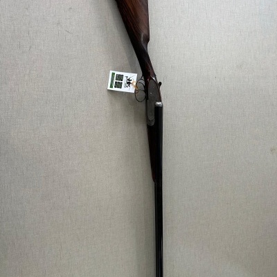 Espingarda de caça com coronha de madeira escura e cano metálico pendurada na parede