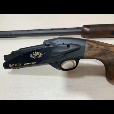 Espingarda Beretta UGB25 Xcel com corpo preto, detalhes dourados e cabo em madeira texturizada
