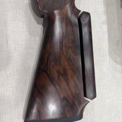 Coronha em madeira escura para carabina com apoio ajustável sobre tecido claro