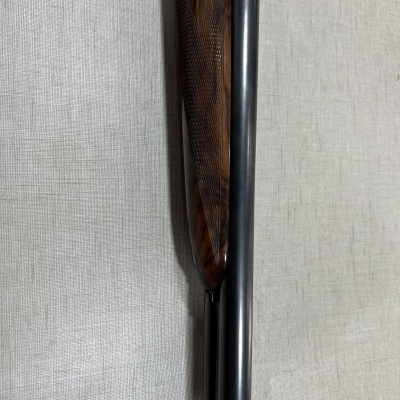 Parte de espingarda com coronha em madeira castanha e cano preto