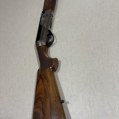 Espingarda com coronha e punho em madeira castanha com textura natural e partes metálicas cinza