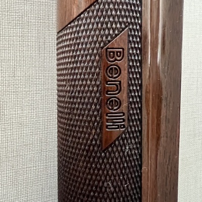 Peça de madeira com textura e inscrição Benelli em relevo junto a moldura de madeira