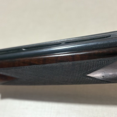 Parte de espingarda com madeira castanha e metal preto com textura triângulo