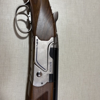 Espingarda Beretta 694 com corpo metálico prateado e coronha em madeira castanha