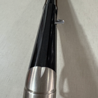 Cano longo de arma de fogo preto com ponteiro prateado e base em madeira