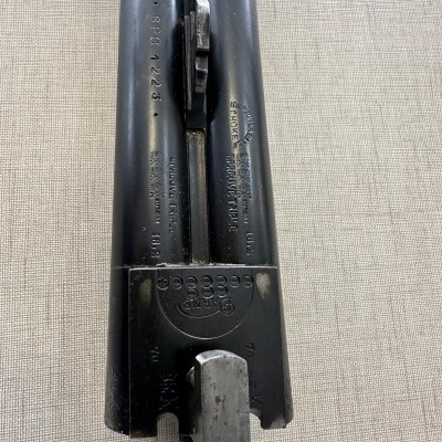 Peça metálica preta de arma de fogo sobre tecido claro texturizado