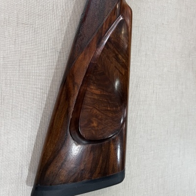 Coronha de madeira escura polida com coronha preta contra fundo cinza