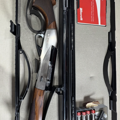 Espingarda Benelli Ethos Sport em caixa com manual vermelho e cartuchos.