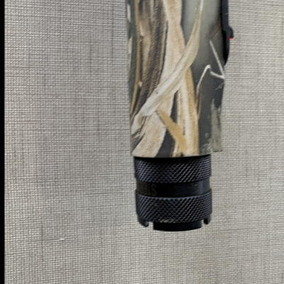 Objeto cilíndrico com padrão camuflado e extremo preto texturizado