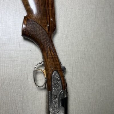 Arma de caça com detalhes em madeira e metal sobre fundo cinzento