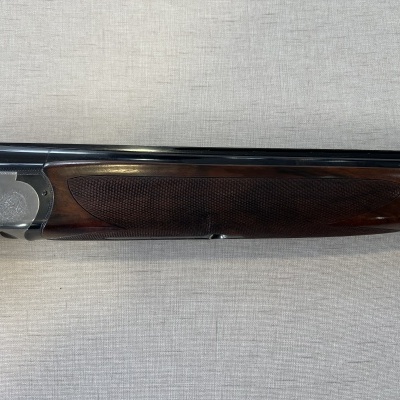 Parte inferior de espingarda com madeira escura e metal prateado