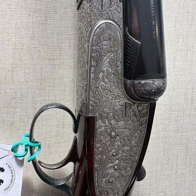 Espingarda com detalhes metálicos gravados e acabamento em madeira escura