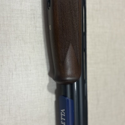 Coronha em madeira escura e cano azul de espingarda com texto BERETTA