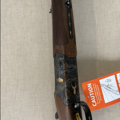 Espingarda de caça com acabamento em madeira e metal com gravações e detalhe dourado