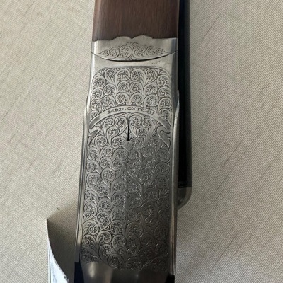 Parte lateral gravada de espingarda com madeira e metal prateado