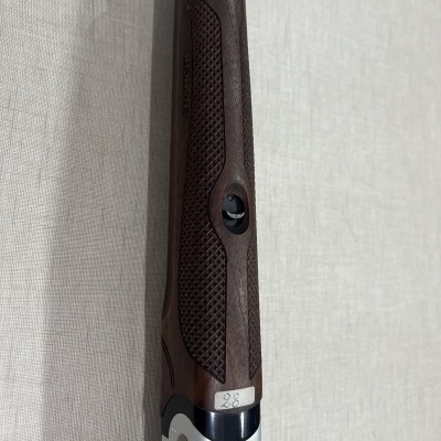 Espingarda com empunhadura de madeira e cano metálico encostada na parede