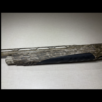 Parte da arma com camuflagem cinzenta e preta sobre fundo claro