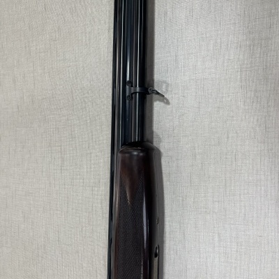 Espingarda com cano duplo em metal negro e coronha em madeira escura com textura antiderrapante