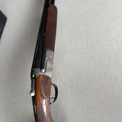 Espingarda com coronha de madeira castanha e detalhes metálicos gravados.