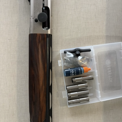 Espingarda com empunhadura em madeira e acessórios para manutenção numa caixa de plástico