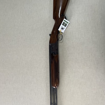 Espingarda de canos duplos em madeira castanho escuro e metal preto com etiqueta próxima ao gatilho