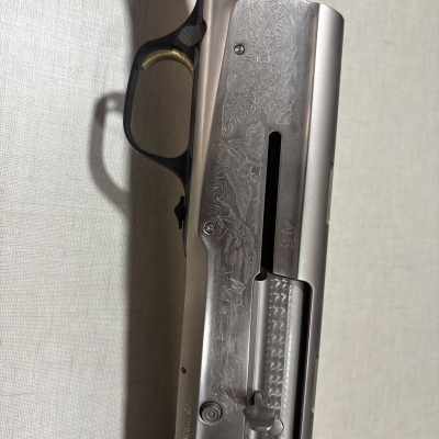 Espingarda prateada com gravações decorativas, gatilho dourado e madeira castanha