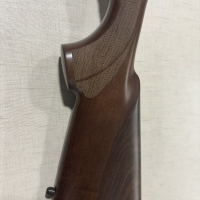 Parte de cabo de arma de fogo em madeira castanha com textura gravada