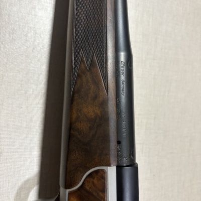 Espingarda com coronha em madeira castanha e cano metálico preto com gravações.