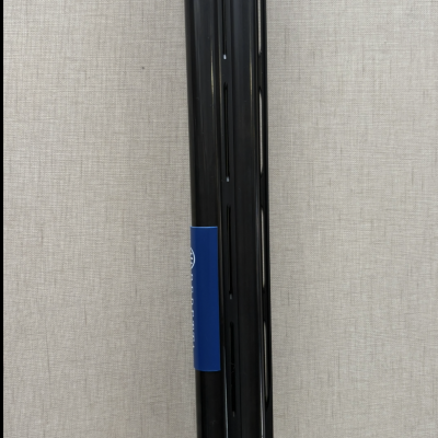 Peça cilíndrica preta com etiqueta azul e fundo cinza texturizado