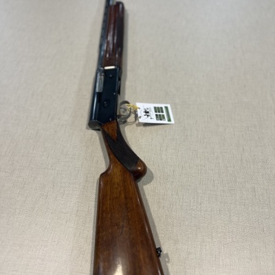 Rifle com coronha de madeira e armação preta sobre fundo beige