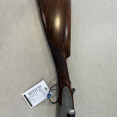 Arma de fogo com coronha em madeira castanha escura e detalhes metálicos