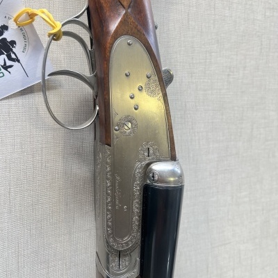 Espingarda de cano duplo com coronha em madeira castanha e ornamentos metálicos prateados