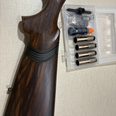 Coronha de arma de madeira e caixa plástica com acessórios metálicos e frasco com tampa laranja