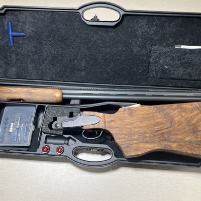 Espingarda desmontada num estojo preto rígido com acessórios e empunhadura de madeira