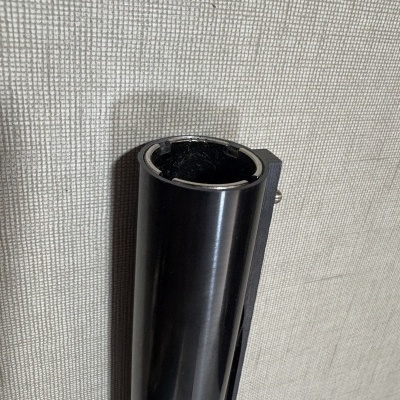 Tubo preto cilíndrico fixado em parede bege com padrão quadriculado