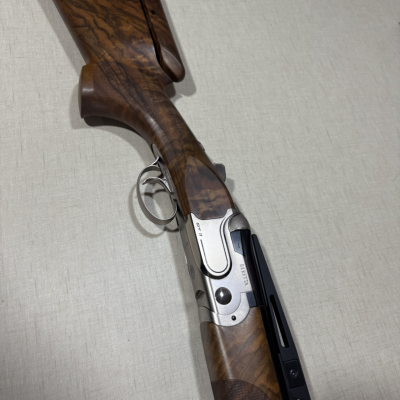 Espingarda Beretta com madeira castanha e detalhes metálicos prateados