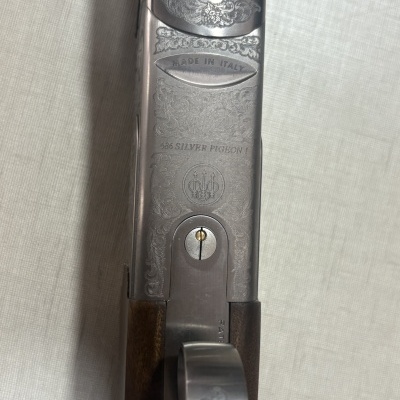 Parte superior de arma de fogo com gravações em metal e punho de madeira