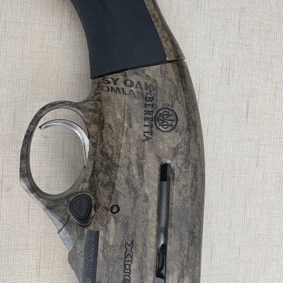 Arma de fogo Beretta com acabamento camuflado e gatilho prateado