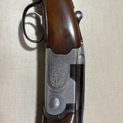 Espingarda com empunhadura de madeira e detalhes metálicos gravados