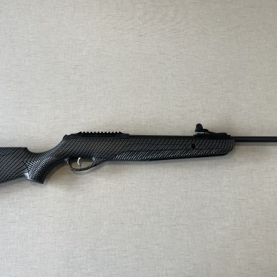 Carabina de ar comprimido preta com padrão fibra de carbono sobre superfície clara