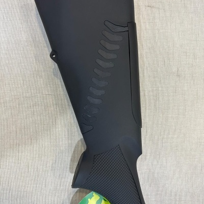 Parte traseira de coronha de arma preta com textura antiderrapante em fundo cinza