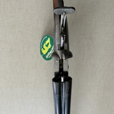 Arma de caça de canos lado a lado com cabo em madeira e canos metálicos pretos