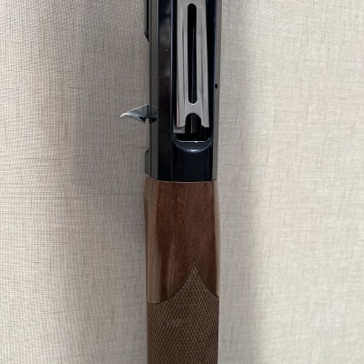 Espingarda com coronha de madeira castanha e mecanismo metálico preto